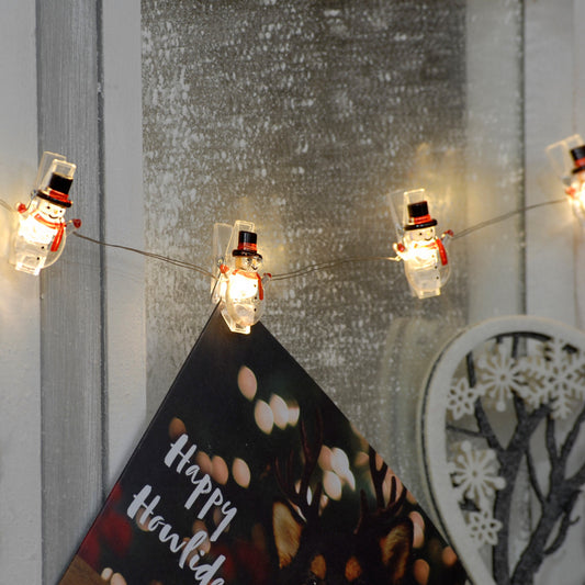 Snowman design peg led lights shown hanging on a wall with Christmas cards hanging from the pegs