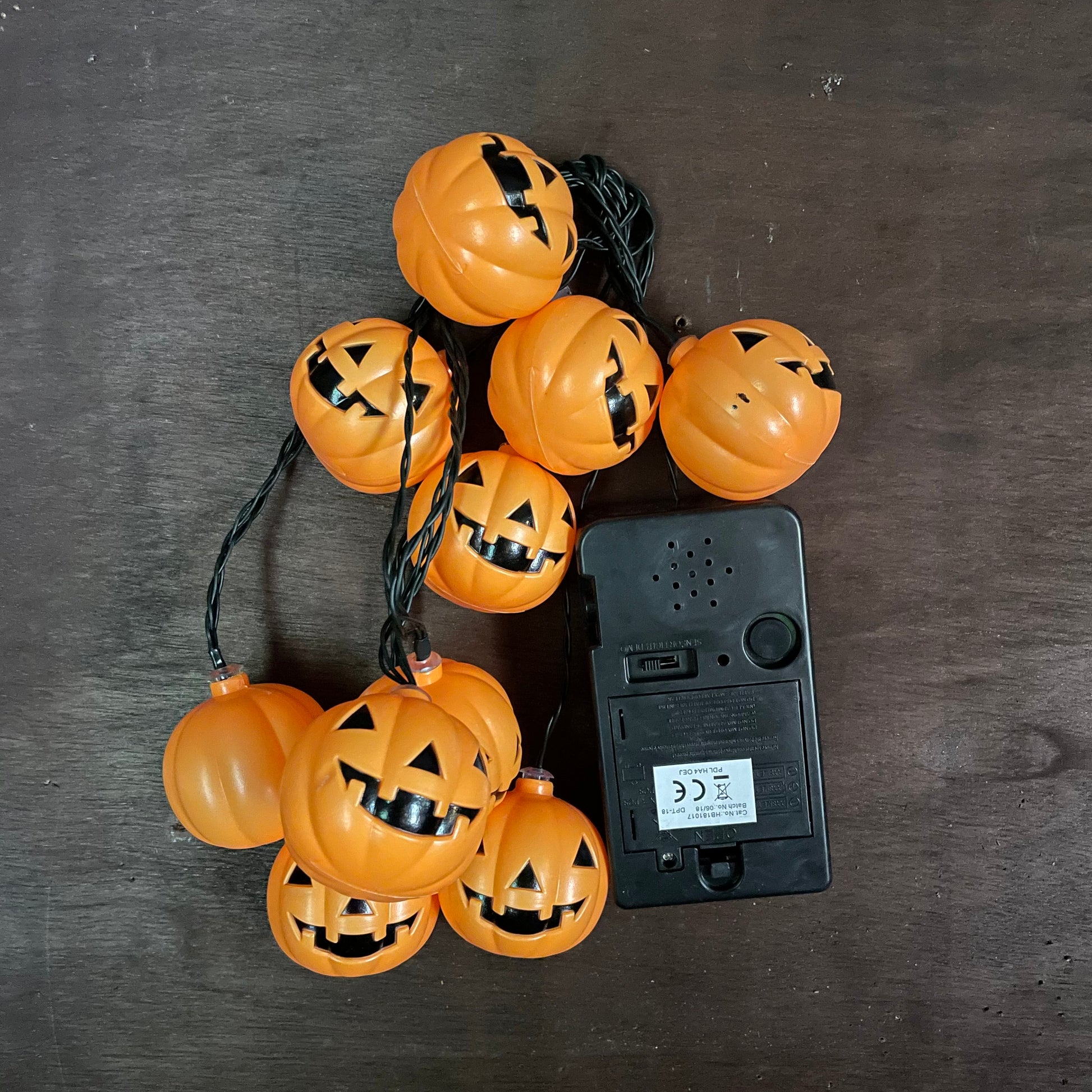 Orange LED pumpkin lights clumped together on a plain backgroud next to the battery box to show of the lights clearer